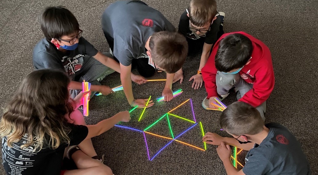 3rd 4th and 5th graders work together to make a tessellation from glow sticks