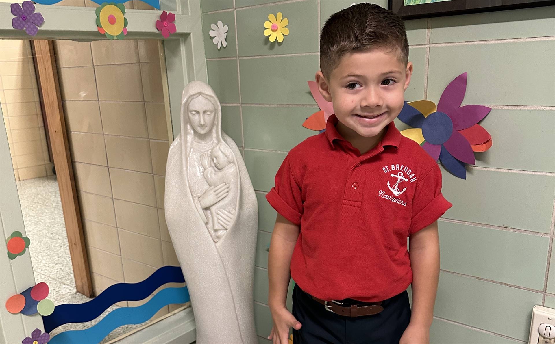 student poses by Mary in his full uniform