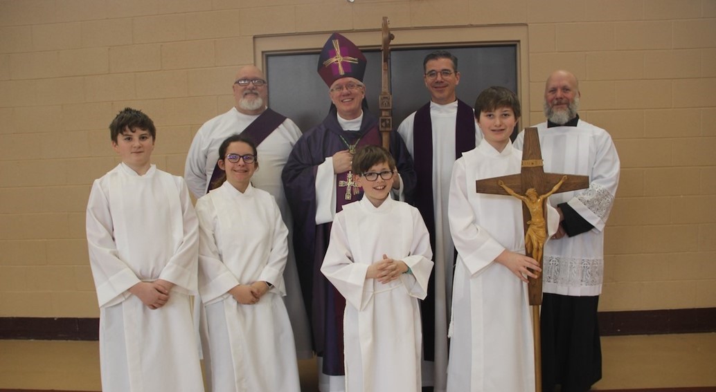bishop woost poses for a picture with servers after a school mass