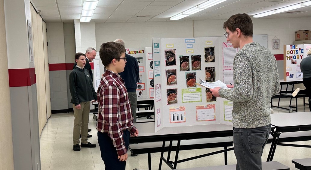 student presents science fair project to judge